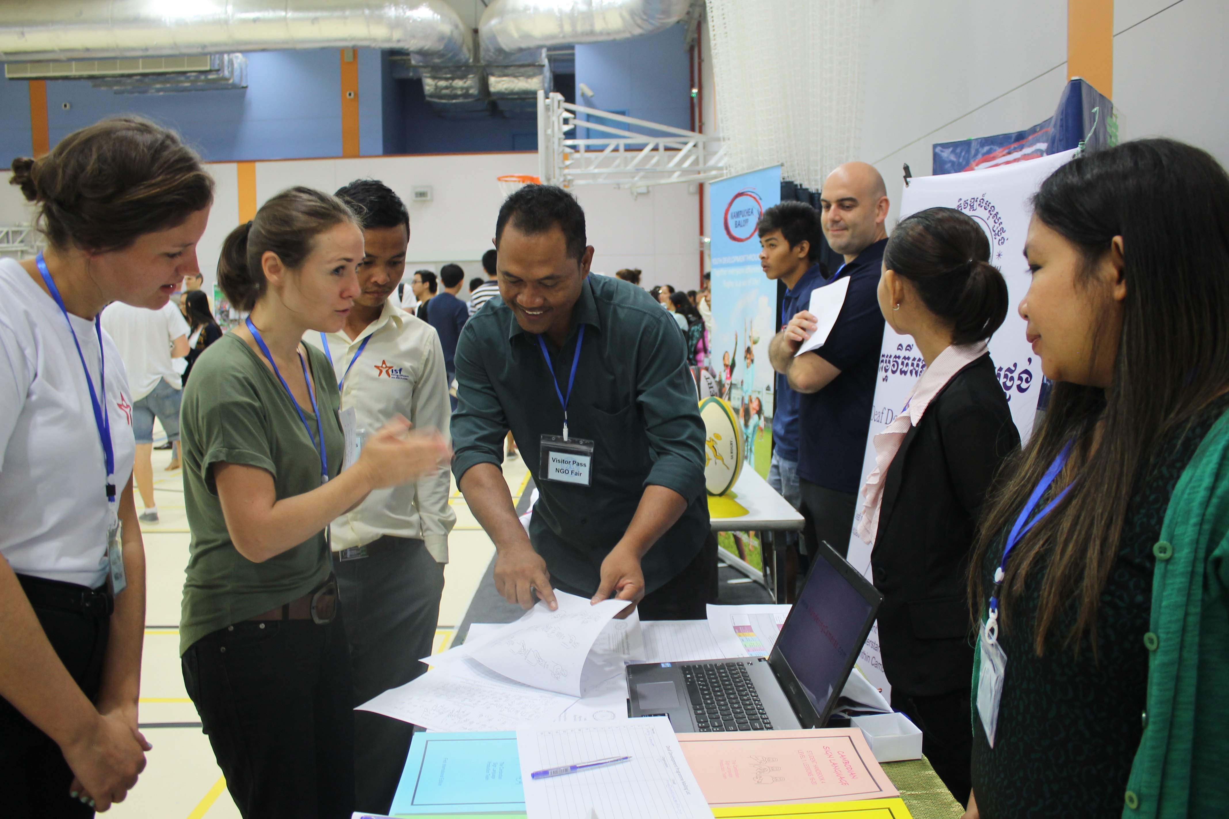 Sam Ath of DDP teaches Jenny of ISF a few Cambodian signs  at the International School of Phnom Penh NGO fair