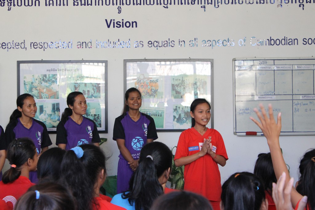 New Day Cambodia representative speaking about her team as the Deaf Amazons look on